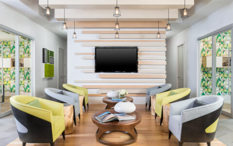 Six chairs alternating between blue and green in front of a flatscreen television