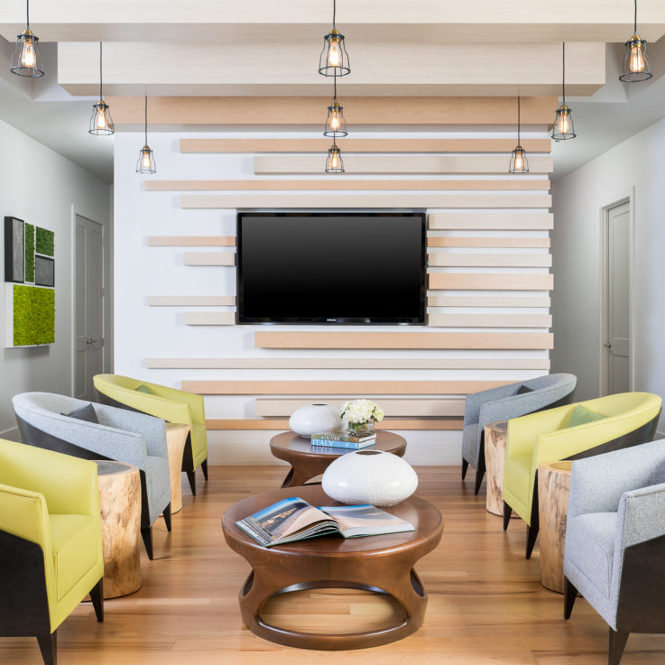 Six chairs alternating between blue and green in front of a flatscreen television