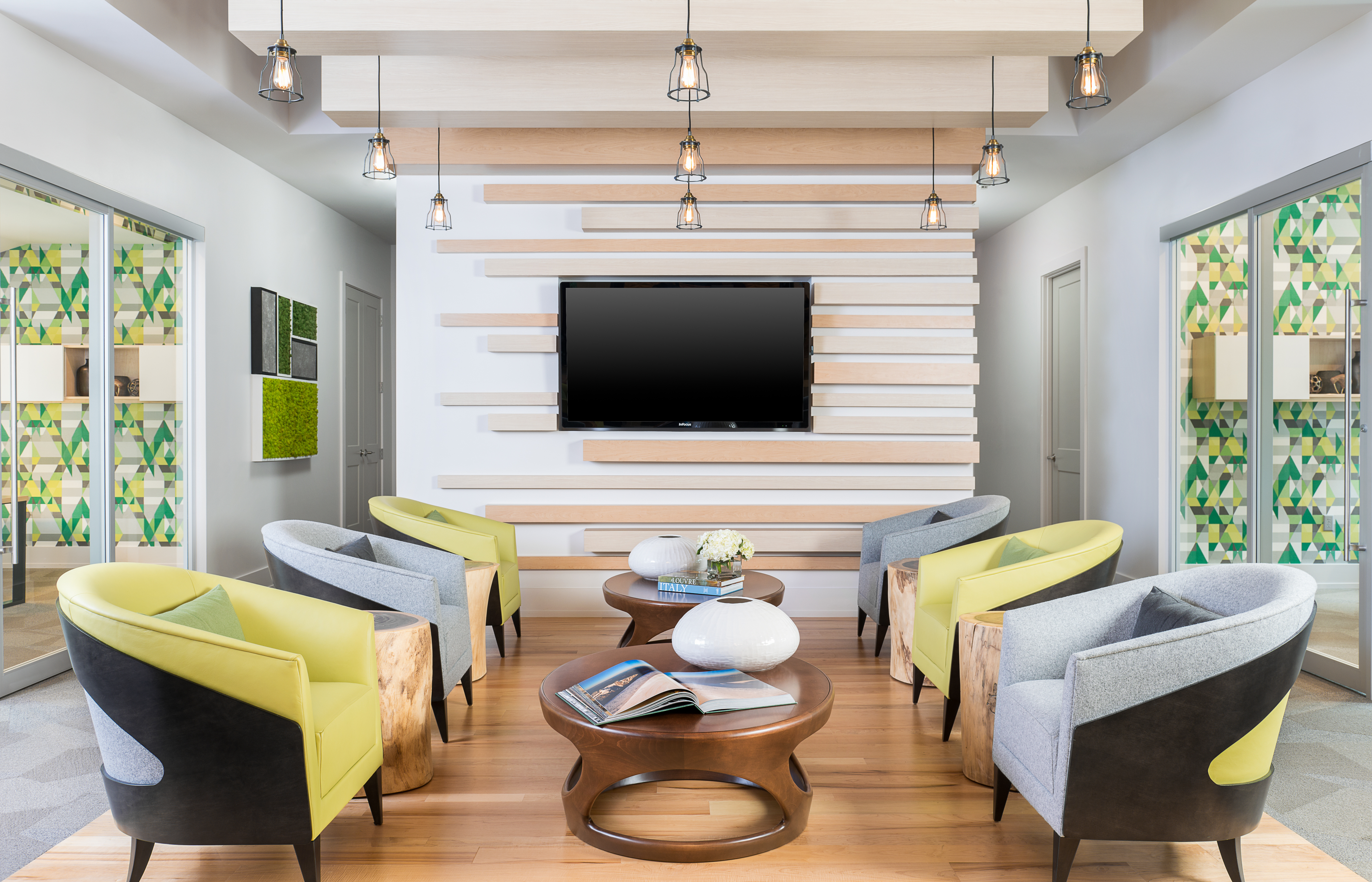 Six chairs alternating between blue and green in front of a flatscreen television