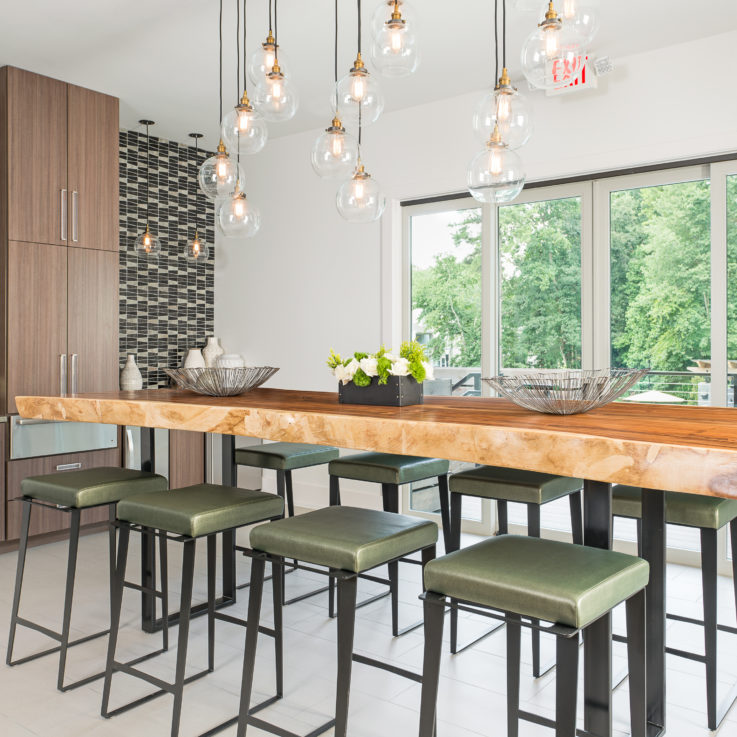 High wooden table with eight stools below hanging lights