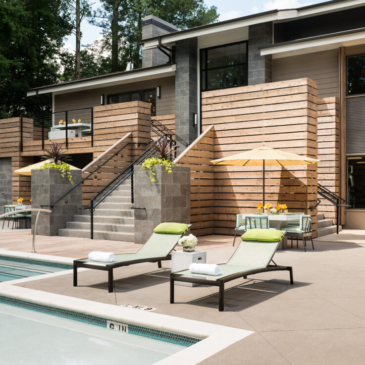 Beach chairs next to a pool with green pillows