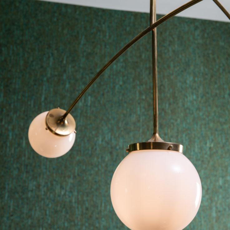 Closeup of a hanging light fixture in front of a green wall