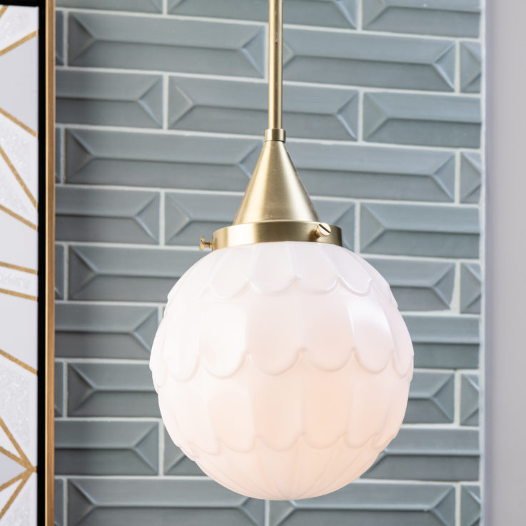 Hanging light fixture in front of a green brick wall