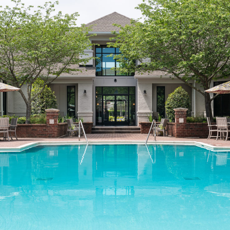 Outdoor pool with two tables beneath umbrellas