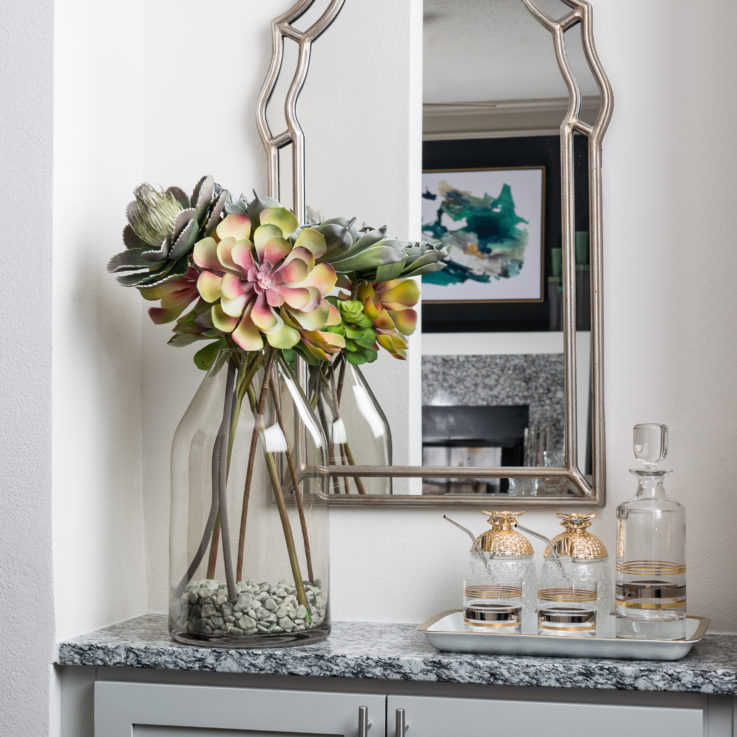 Cabinet with a granite countertop below a large framed mirror