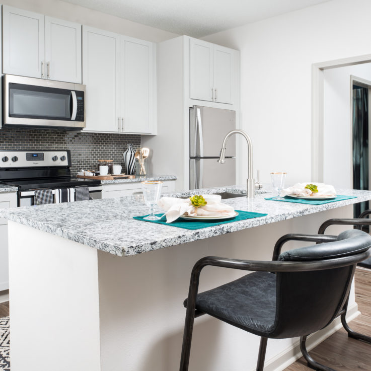 Kitchen area with white cabinets, a granite countertop, and stainless steel appliances