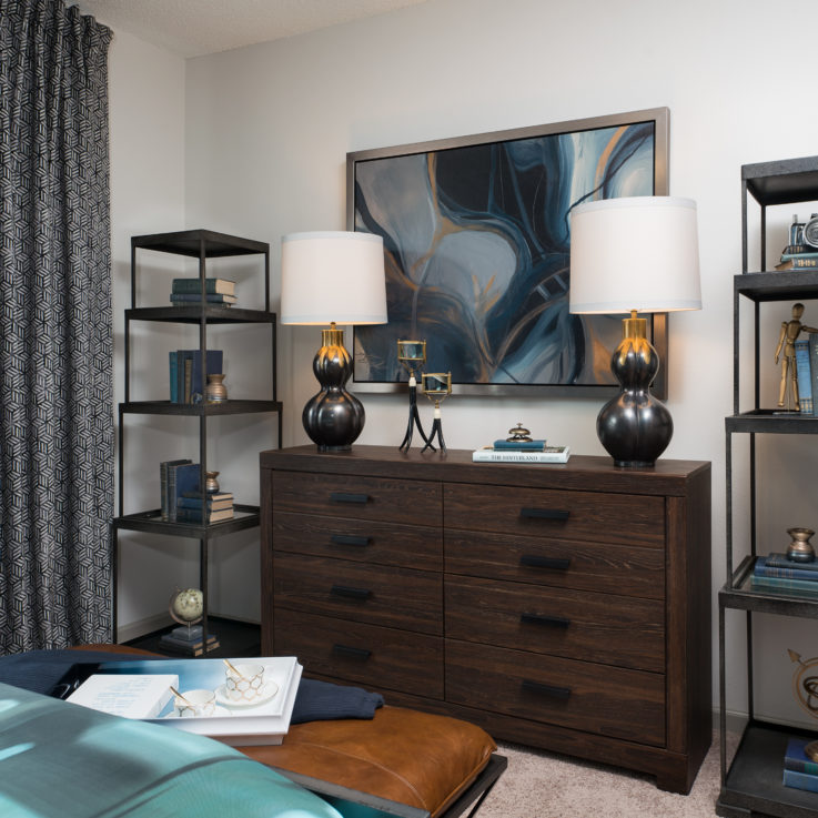 Dark brown dresser with two lamps next to two sets of shelves