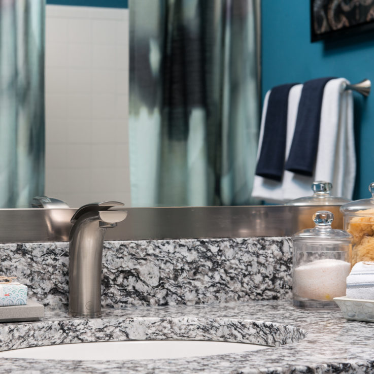 Bathroom sink with a granite countertop and a large framed mirror