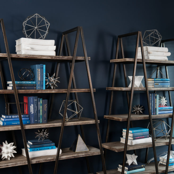 Wooden shelves with books and art against a dark blue wall
