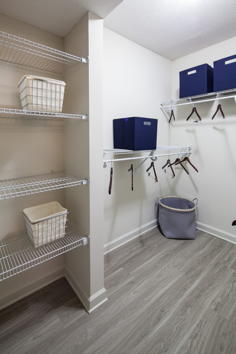 Closet storage area with white shelves and dark blue containers