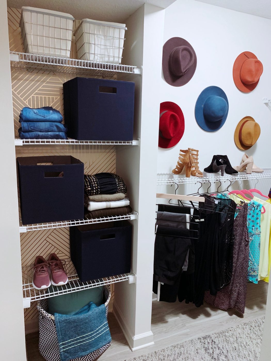 Storage closet with white shelves and various containers and clothes