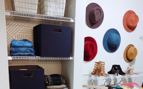 Storage closet with white shelves and various containers and clothes