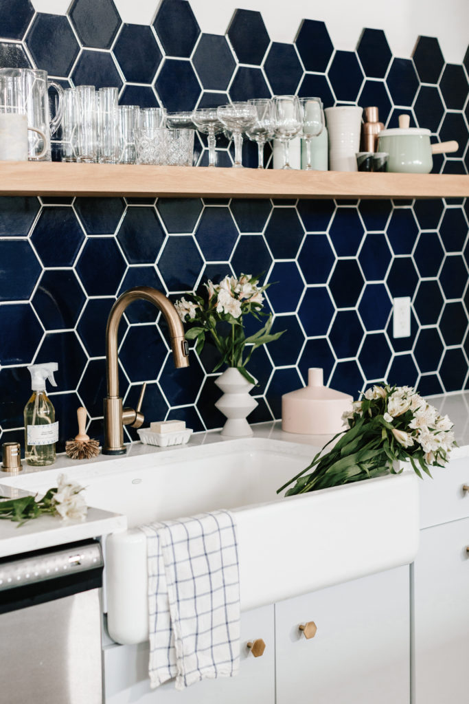 Kitchen with white cabinets and countertops and dark blue hexagon tiles on the wall