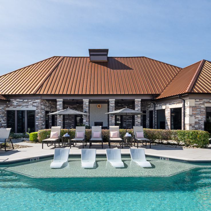 Outdoor pool with beach chairs and pink pillows