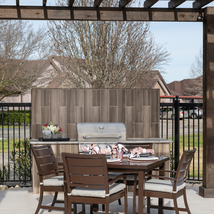 Large grill behind wooden table with four chairs