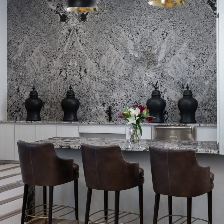 Three brown barstools in front of a granite countertop