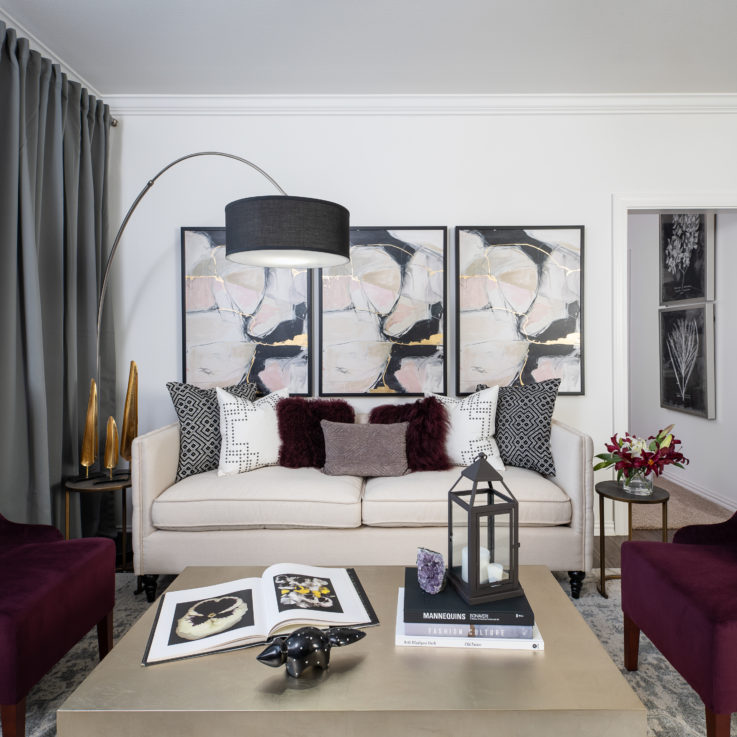 Seating area with white couch, purple chairs, and three paintings