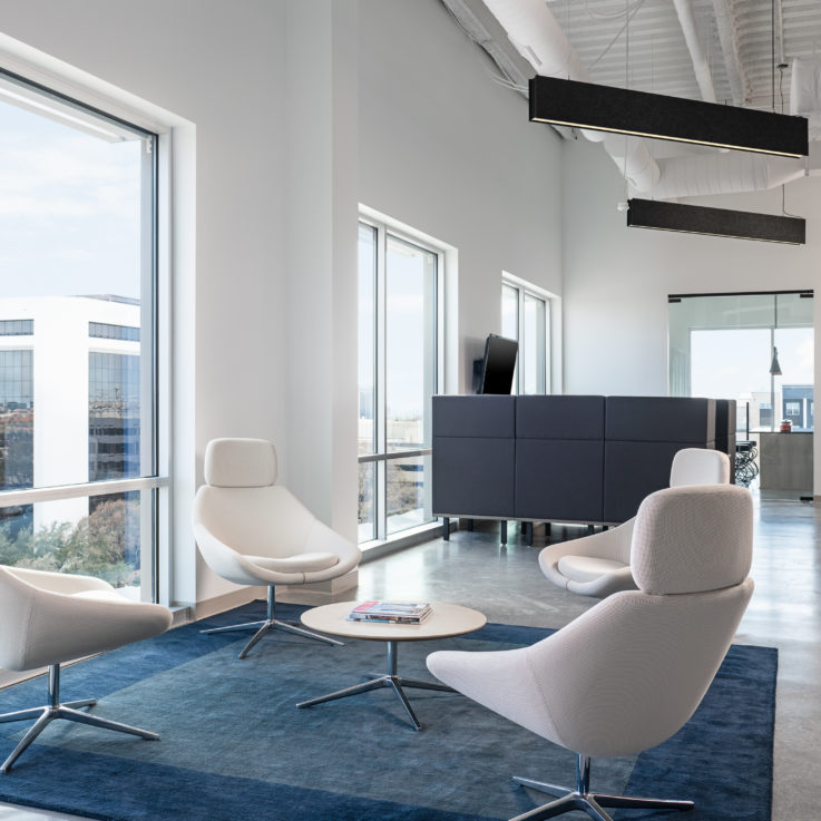 Seating area with four white chairs and a blue rug