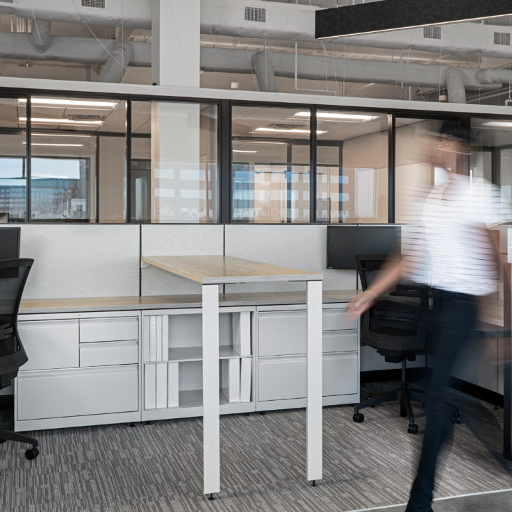 Two cubicles with white desks and black office chairs