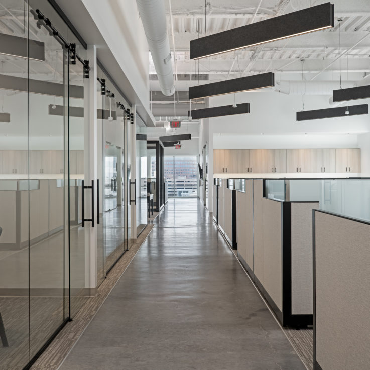 Rows of cubicles next to glass offices