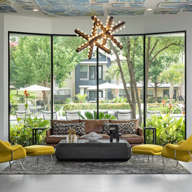 Brown couch and two yellow chairs in front of large windows