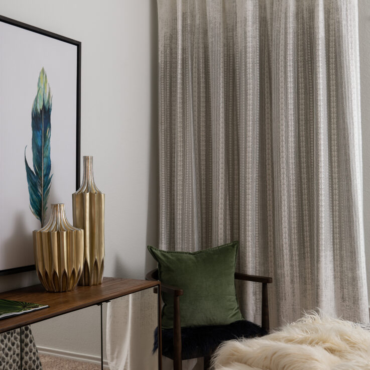 Dresser, two paintings, a chair with a green pillow and beige curtains