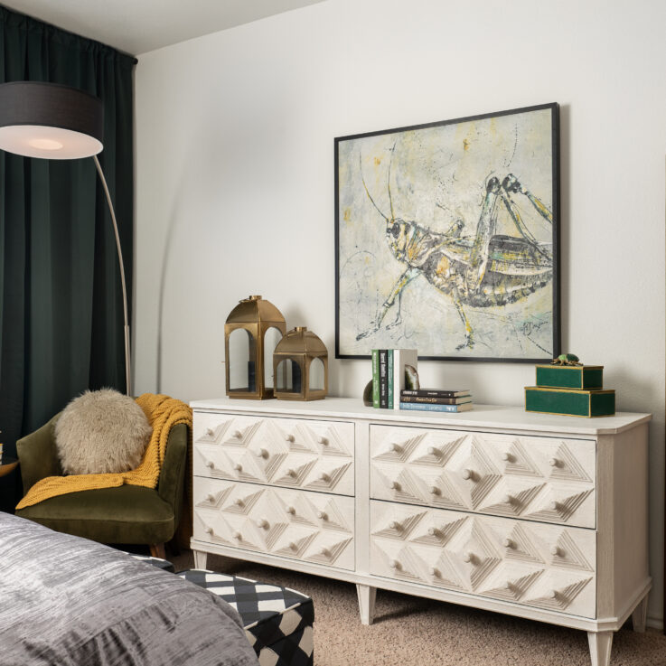 White dresser below a painting of a grasshopper