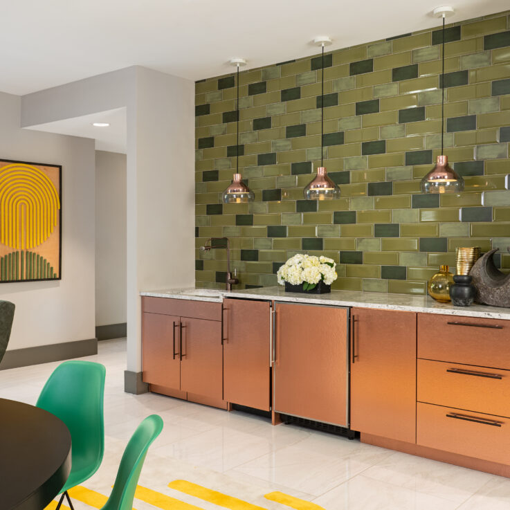 Sink on a granite countertop with wooden cabinets and a green tiled wall