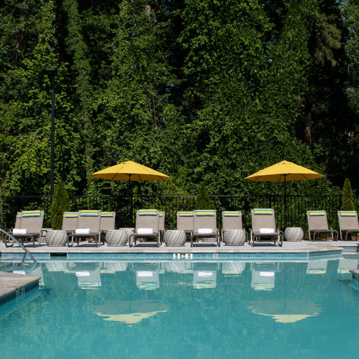 Outdoor pool with gray beach chairs and yellow umbrellas