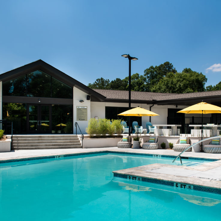 Outdoor pool with circular chairs beneath yellow umbrellas