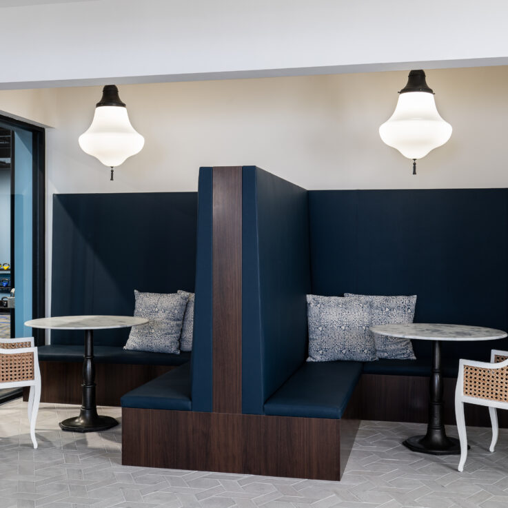 Two blue cushioned booths with circular tables and white wicker chairs