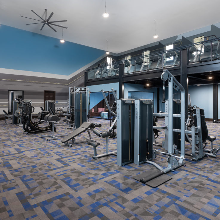 Two story workout room filled with various weights and machines