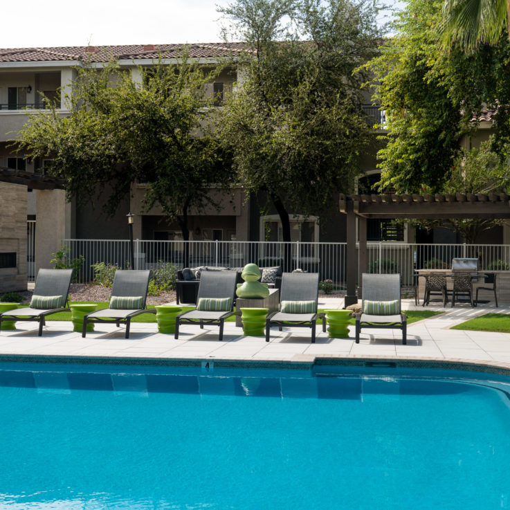 Outdoor pool with beach chairs and green tables