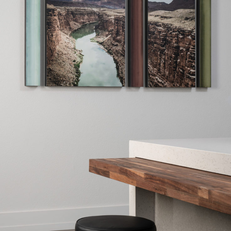 Two paintings of the grand canyon behind a wooden table and black stools