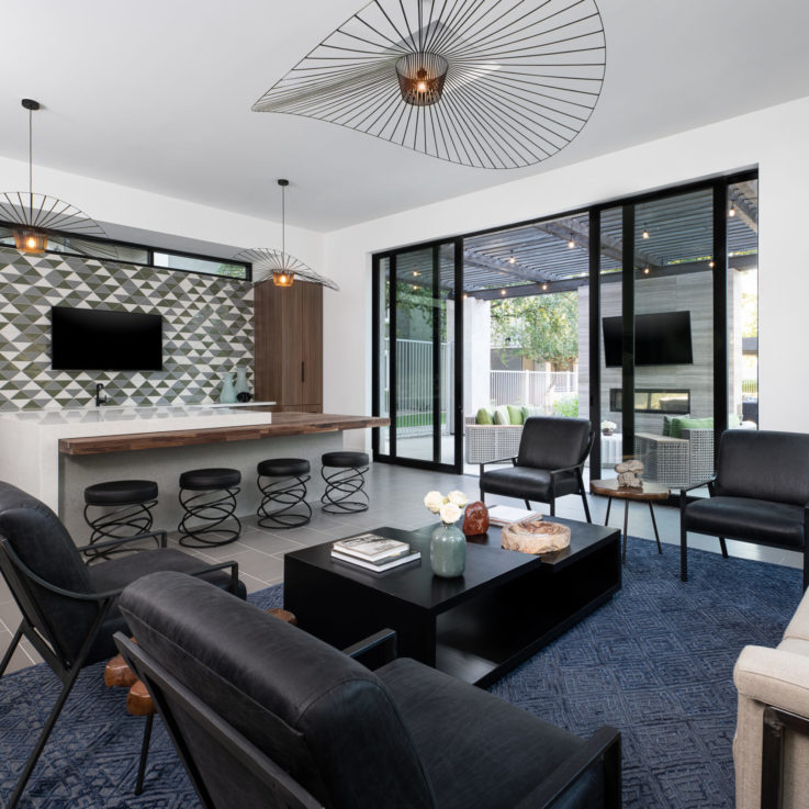 Seating area with black chairs and a dark blue carpet with open glass doors