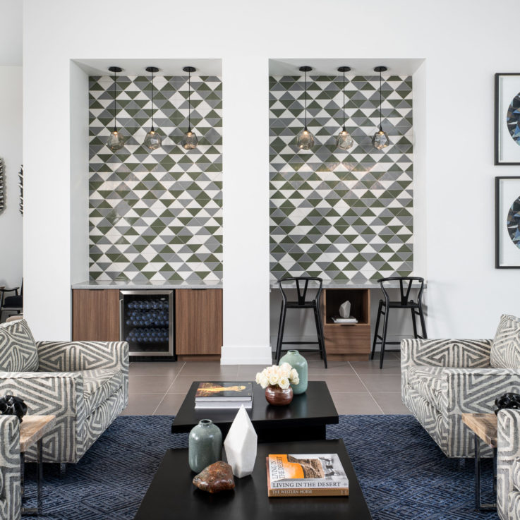 Seating area with a blue carpet and white, blue, and green tiles on the wall