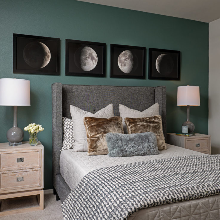 Twin bed in front of a green wall with paintings of the moon