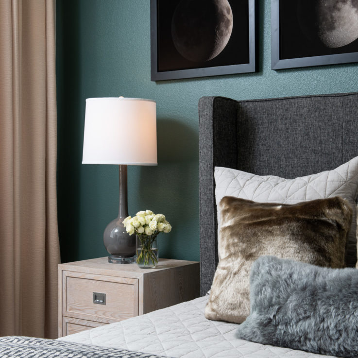 Light wooden bedside table with a lamp and a clear glass container with white roses