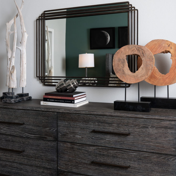 Dark stained wooden dresser topped with art and a mirror