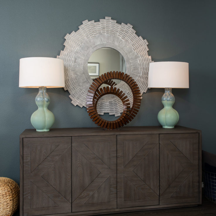 Dark wooden cabinet topped with art in front of a blue wall