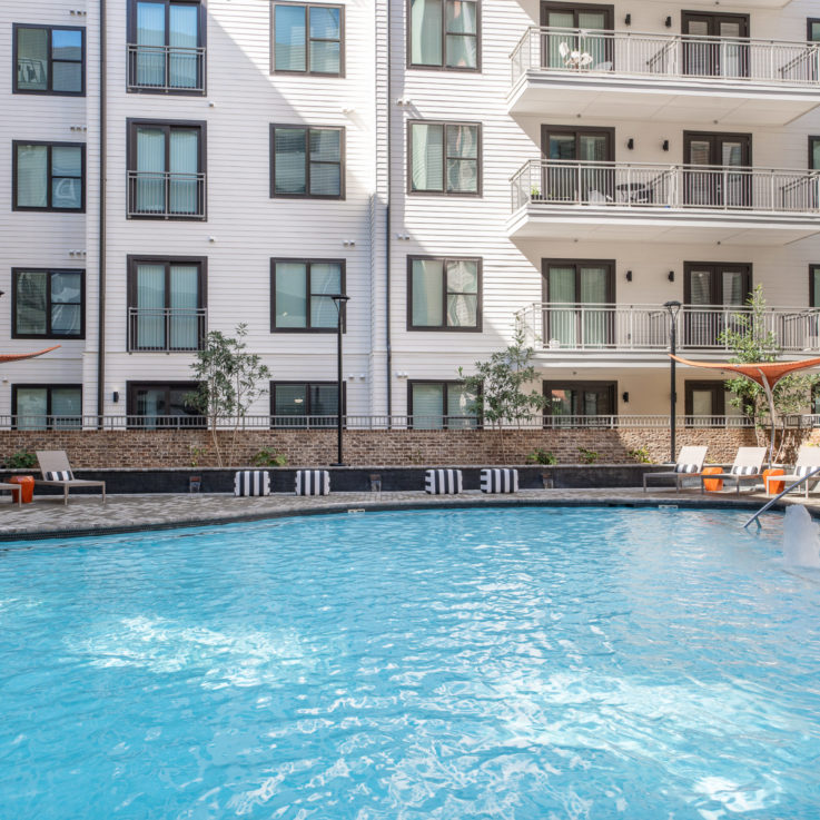 Outdoor pool with beach chairs and orange umbrellas