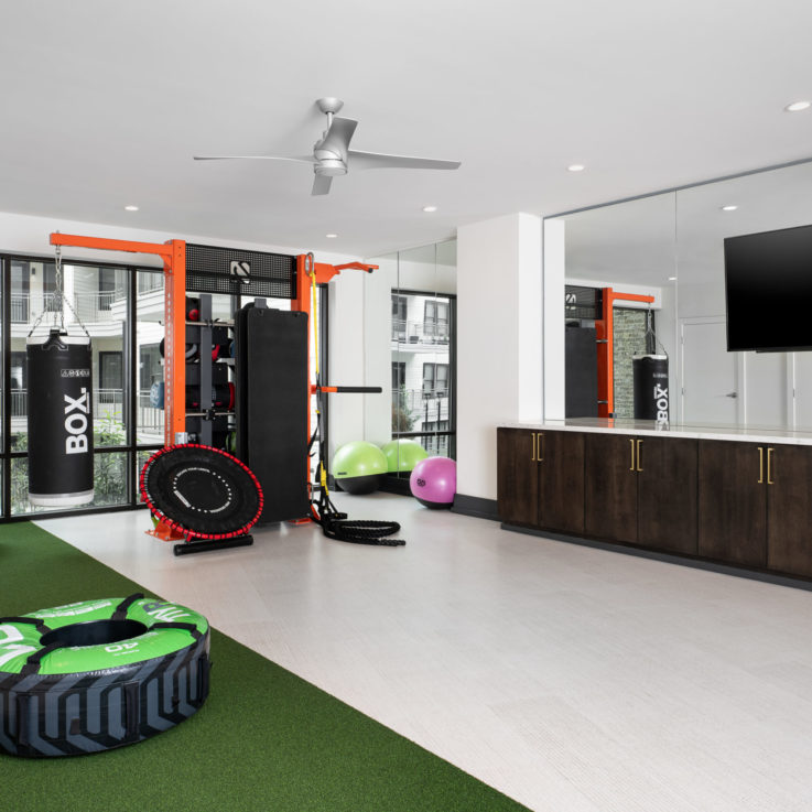 Workout area with various machines and weights with a mirror wall