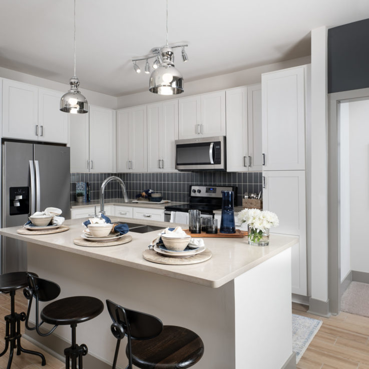 Kitchen area with white cabinets, white countertops, and stainless steel appliances