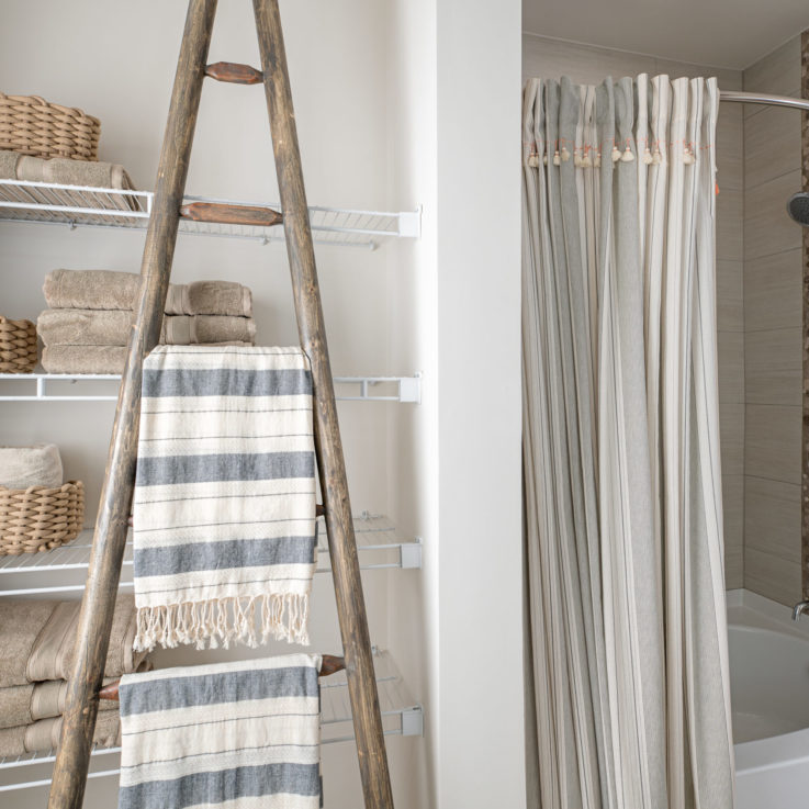 Bathroom tub and shelving with beige towels