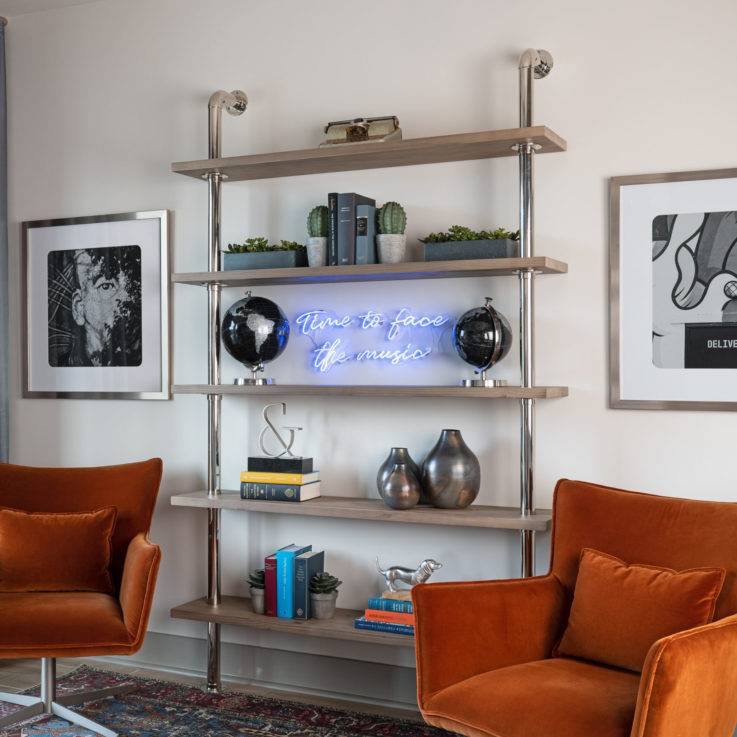 Two orange chairs and paintings with shelving in between them