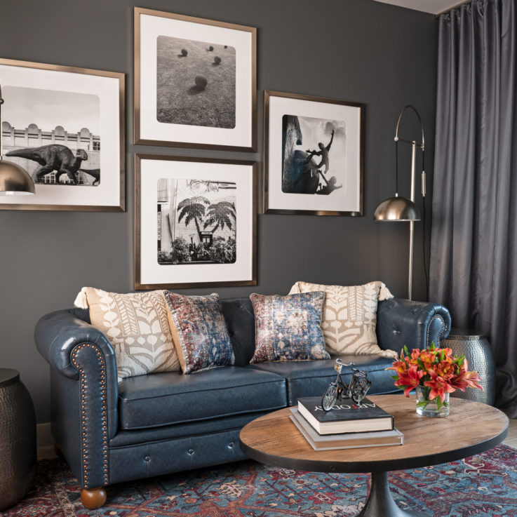 Dark blue couch with four black and white paintings above