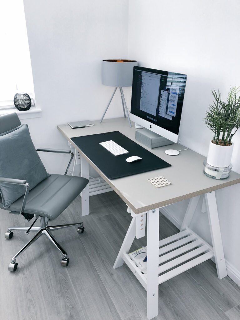 Empty chair and desk with a computer in the corner of a room