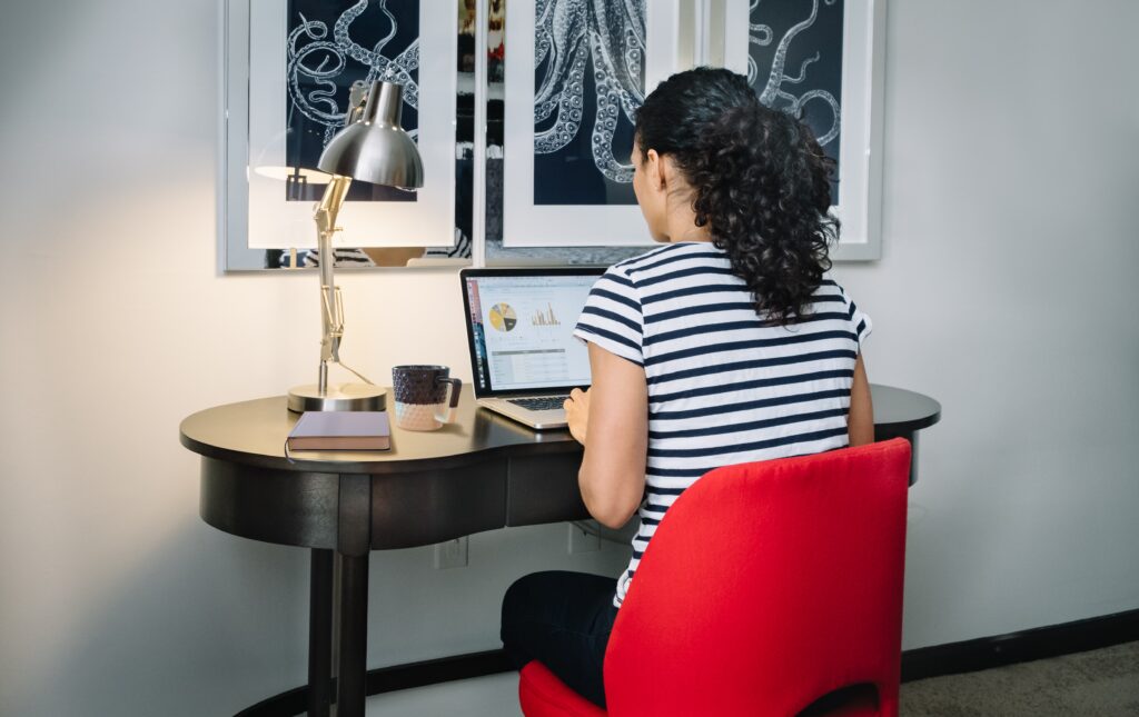 Woman-sitting-in-red-chair-at-desk-typing-on-computer