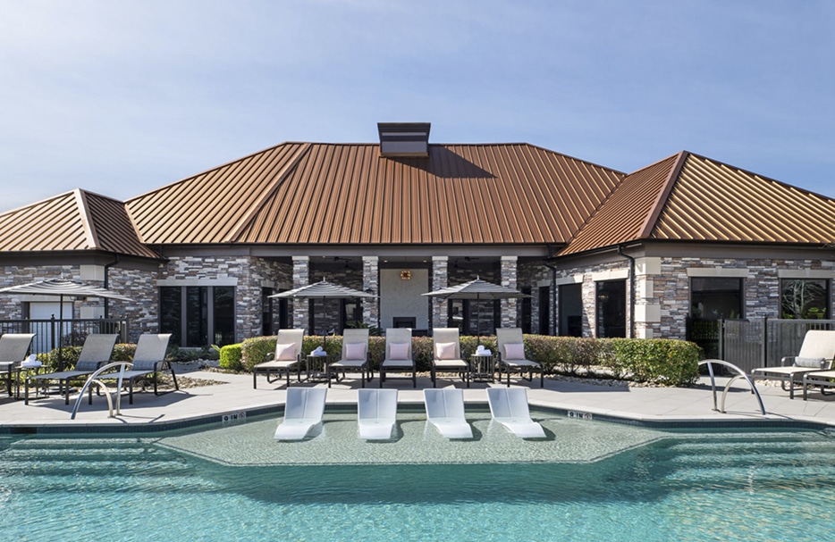 Exterior of a clubhouse next to a pool with beach chairs