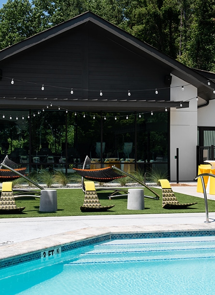 Pool with hamocks and chairs next to a clubhouse